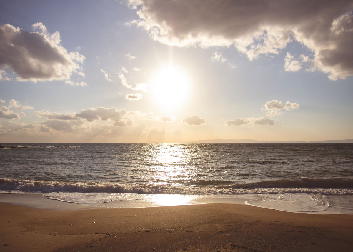 The setting sun shining over a beach scene