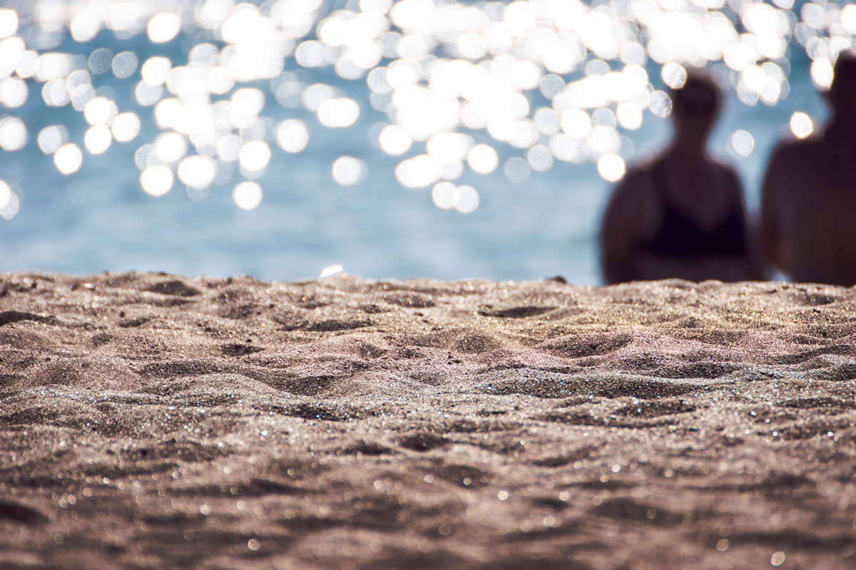 A beach scene showing sand, sea and some beachgoers